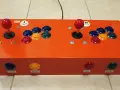 Joystick arcade arancione per retropie su pc, con pulsanti colorati e levette rosse.
