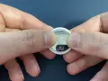 Mani che premono per sostituire la batteria di un AirTag.