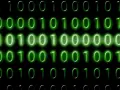 Sequenze di zeri e uno verdi brillano su sfondo nero. Il codice binario, che rappresenta il mb significato, scorre in righe.