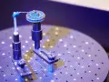 Un oggetto circolare con scanalature è fissato su un supporto. Un braccio metallico con una punta blu si avvicina per analizzarlo. Questo è un esempio di come funziona uno scanner 3D.