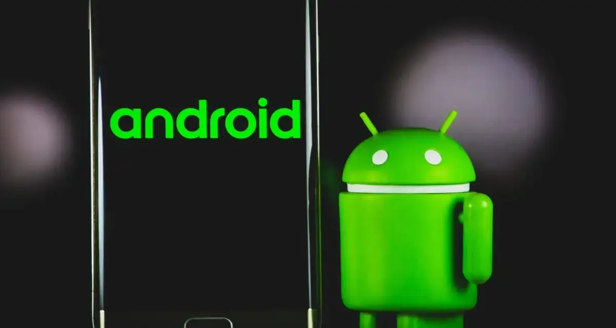 Un robot Android verde accanto a uno smartphone con il logo Android. La sincronizzazione automatica Android è fondamentale per mantenere i dati aggiornati.