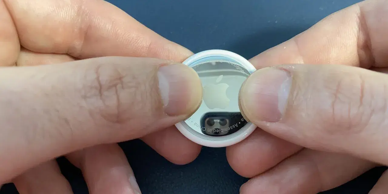 Mani che premono per sostituire la batteria di un AirTag.