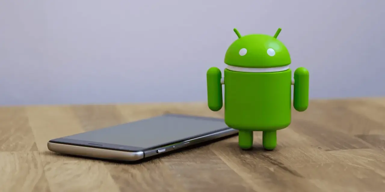 Un cellulare che si impalla, con l'iconico robot verde Android accanto, su un tavolo di legno.