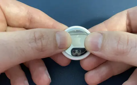 Mani che premono per sostituire la batteria di un AirTag.