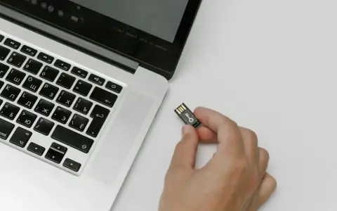 Una mano tiene una chiavetta USB con un simbolo di chiave, pronta per essere inserita in un laptop. Chissà quanto è un terabyte di dati da archiviare!