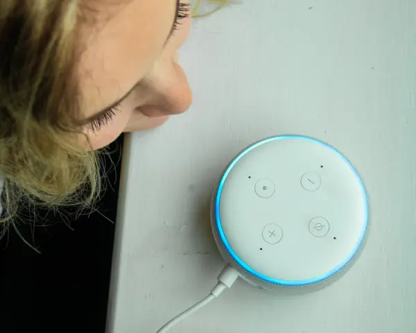 La ragazza si china per chiedere ad Alexa perché è rossa, ma la luce è blu.