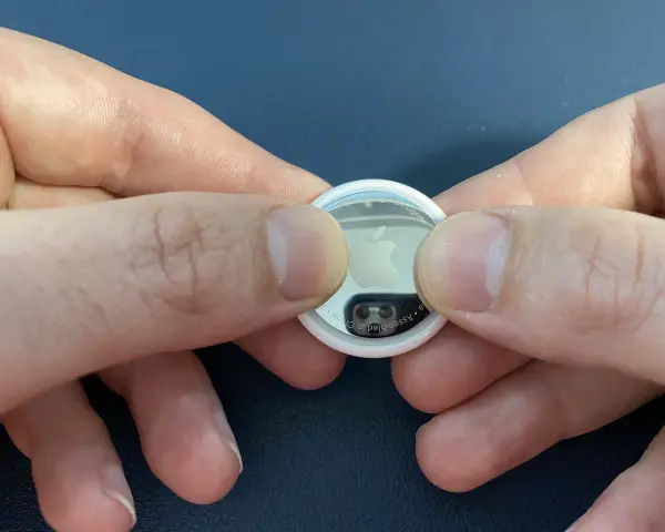 Mani che premono per sostituire la batteria di un AirTag.