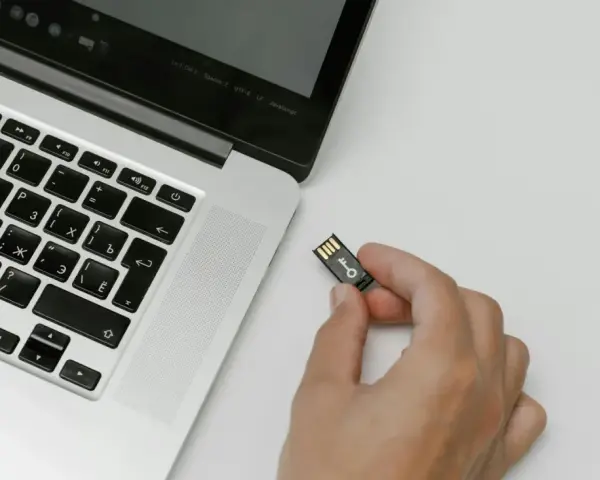 Una mano tiene una chiavetta USB con un simbolo di chiave, pronta per essere inserita in un laptop. Chissà quanto è un terabyte di dati da archiviare!