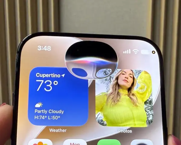 Schermo iPhone con widget meteo e foto. La Dynamic Island mostra un'onda colorata, forse perché Siri non risponde.