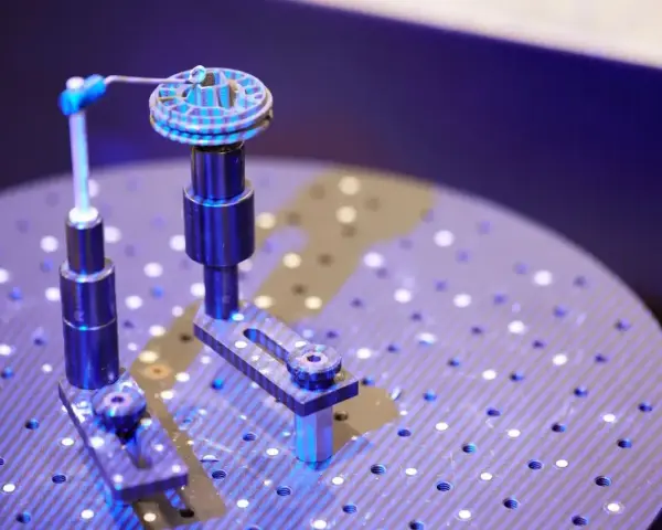 Un oggetto circolare con scanalature è fissato su un supporto. Un braccio metallico con una punta blu si avvicina per analizzarlo. Questo è un esempio di come funziona uno scanner 3D.