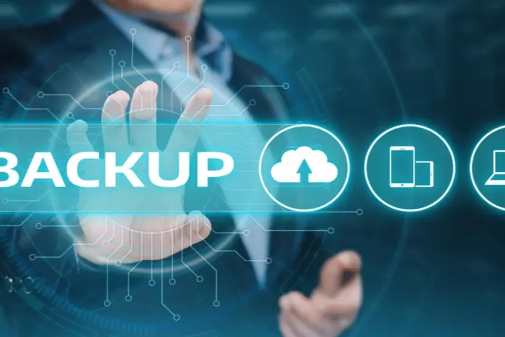 Un uomo tocca la parola "BACKUP" su uno schermo futuristico, con icone di cloud, smartphone e laptop.