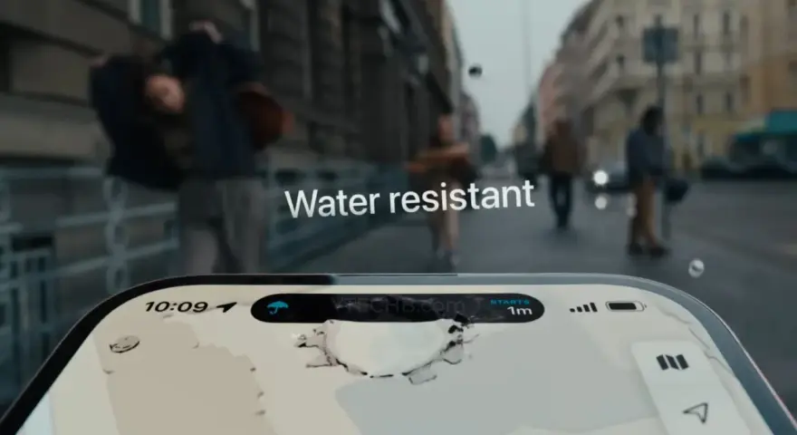 L'iPhone 15 è waterproof. La pioggia cade sulla strada mentre le persone camminano, ma il telefono rimane protetto.