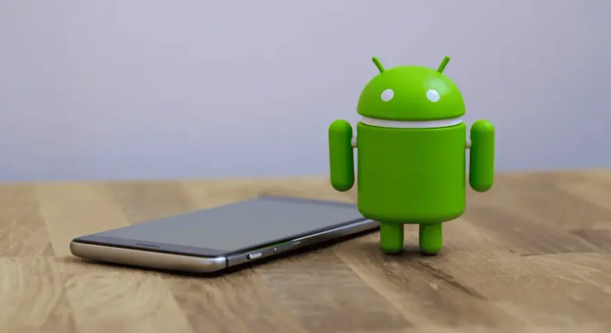 Un cellulare che si impalla, con l'iconico robot verde Android accanto, su un tavolo di legno.