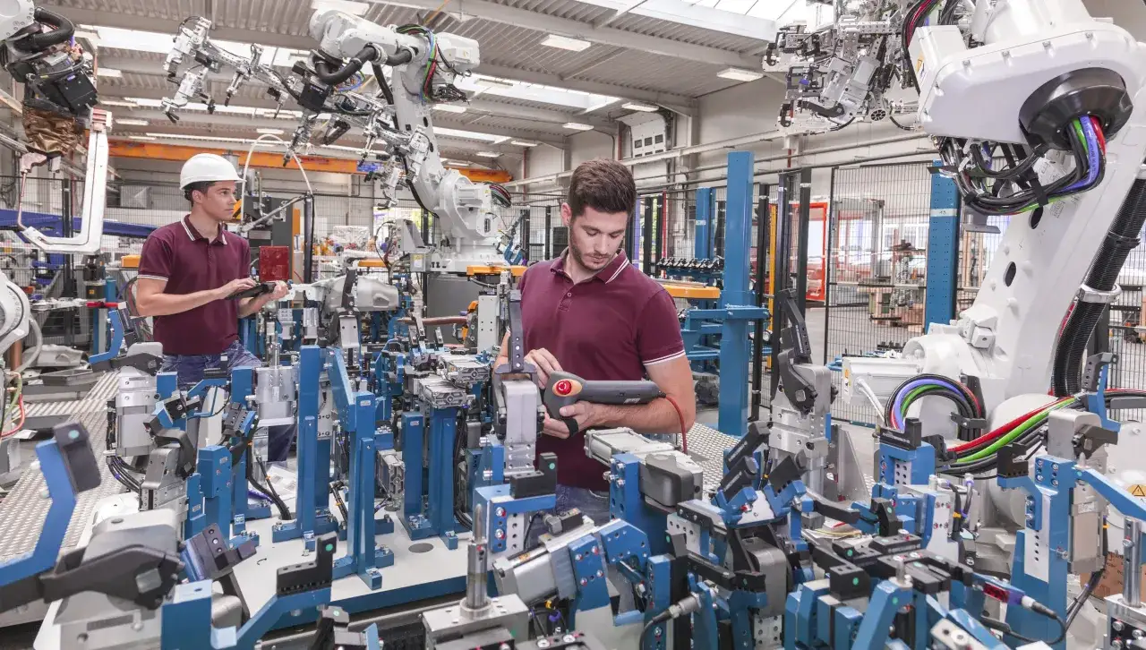 Operai in una fabbrica moderna, con robot e macchinari avanzati, che lavorano per l'industria 5.0.