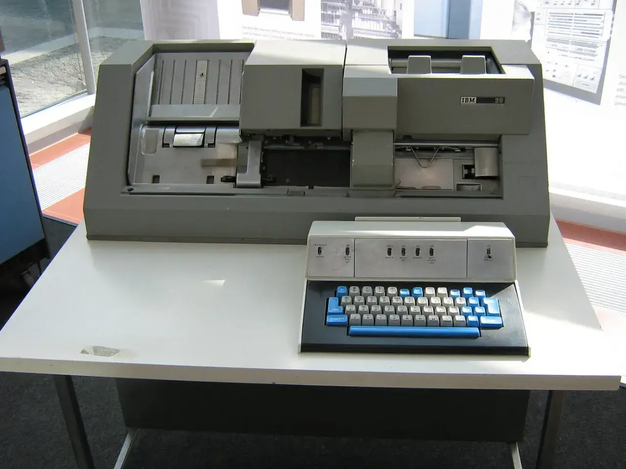 Un computer IBM con tastiera e stampante, pronto a leggere una scheda perforata.