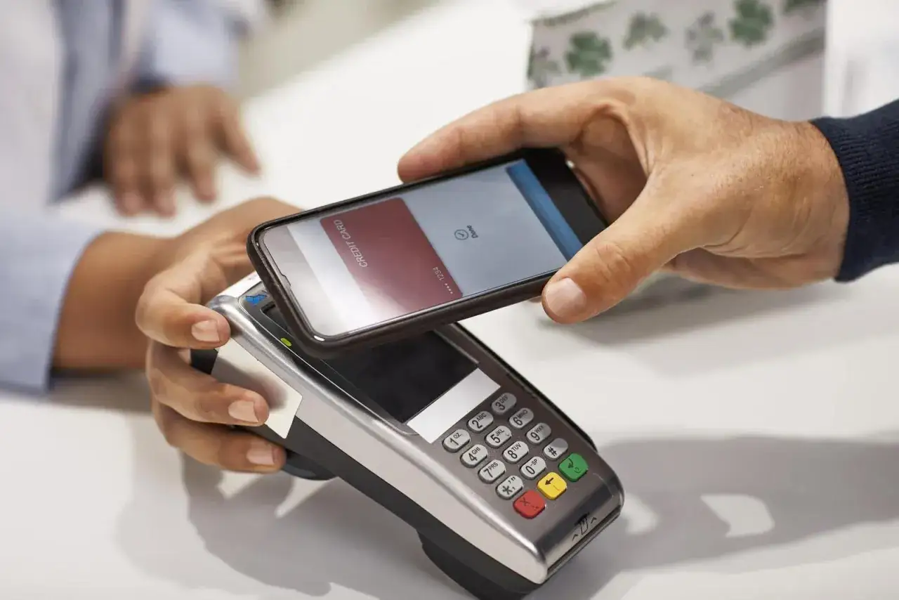 Pagamento contactless con iPhone tramite NFC. Un iPhone viene avvicinato a un POS per completare una transazione.