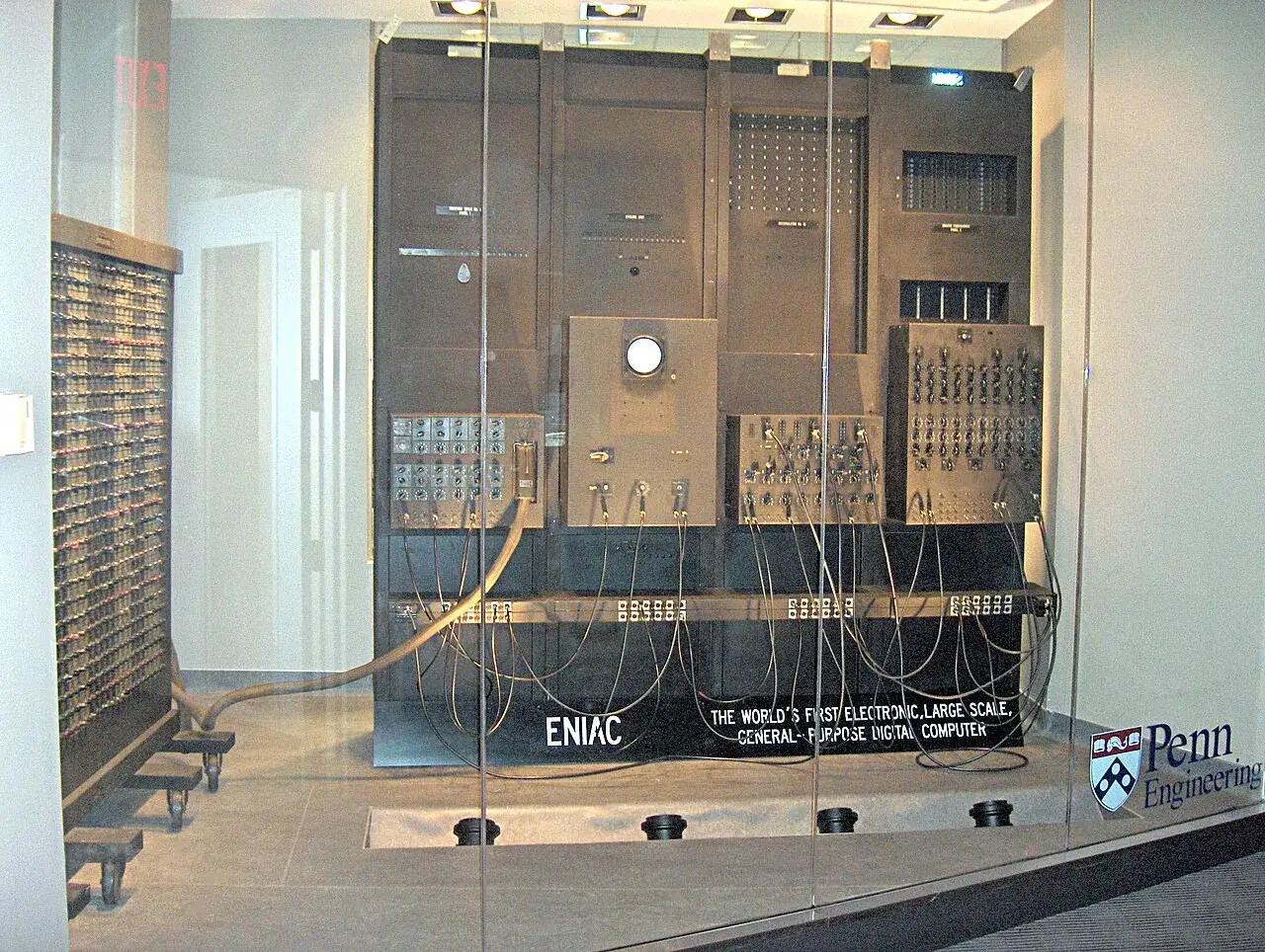 Il computer ENIAC, un gigante elettronico con pannelli e cavi, segna l'inizio dell'era digitale.