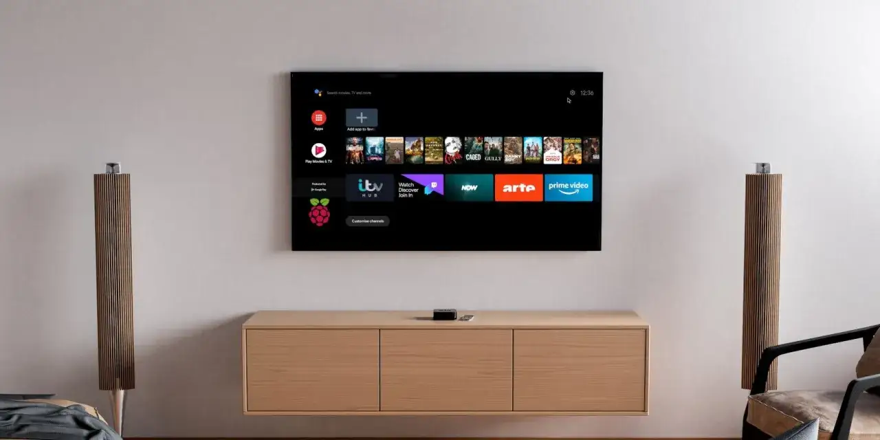 Schermo TV con interfaccia Android, che mostra app di streaming e il logo Raspberry Pi. Un piccolo dispositivo nero, forse un android tv raspberry pi 3, &egrave; posizionato sul mobile.